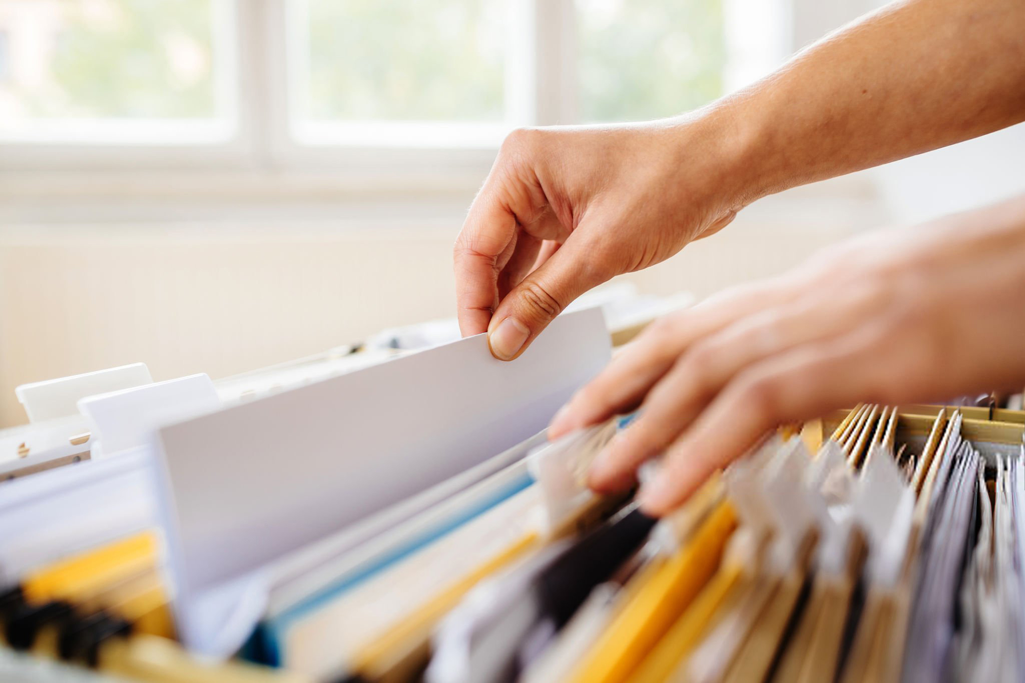 Close-up of hands searching in a file cabinet